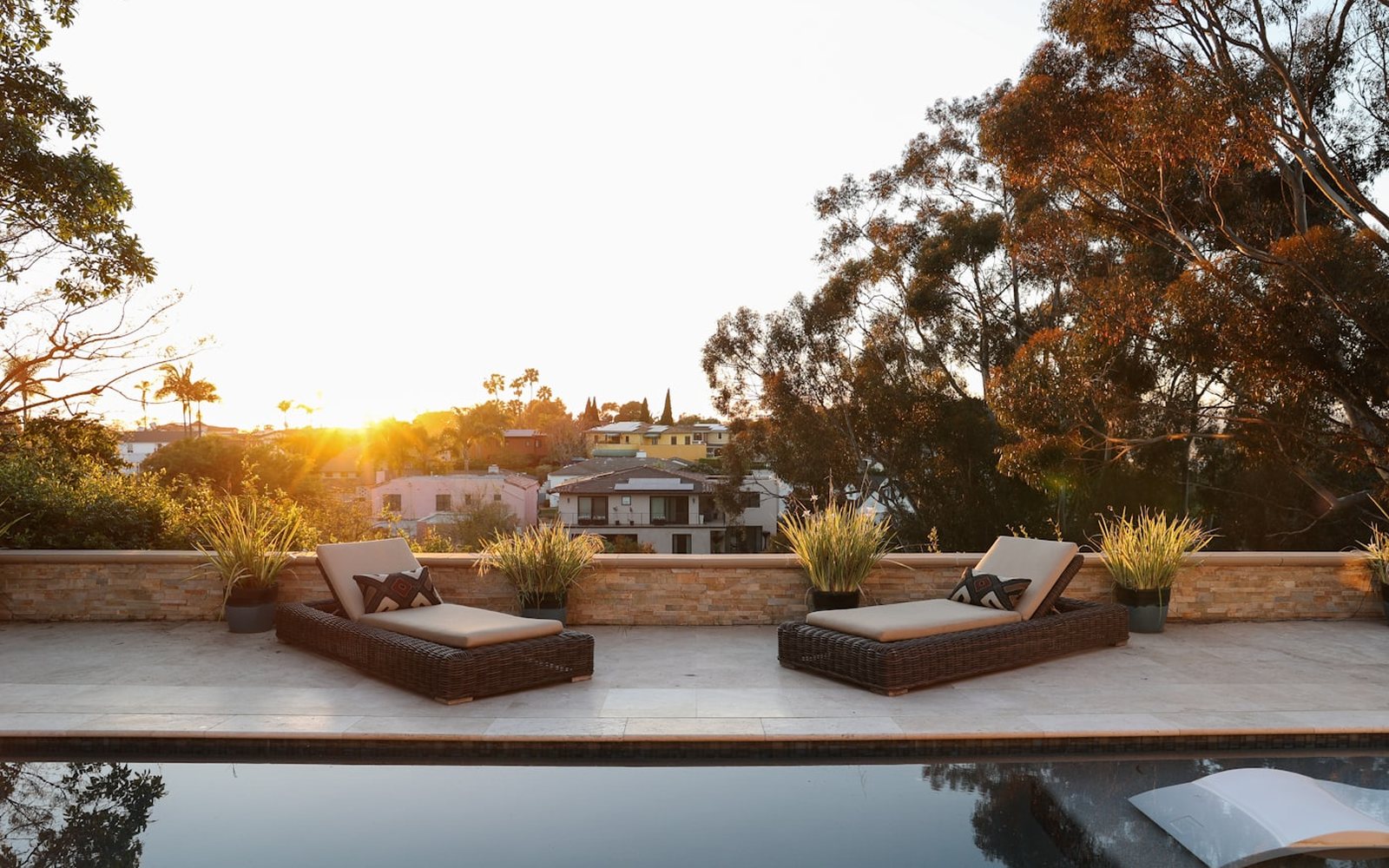 A backyard pool and lounge chairs at sunset