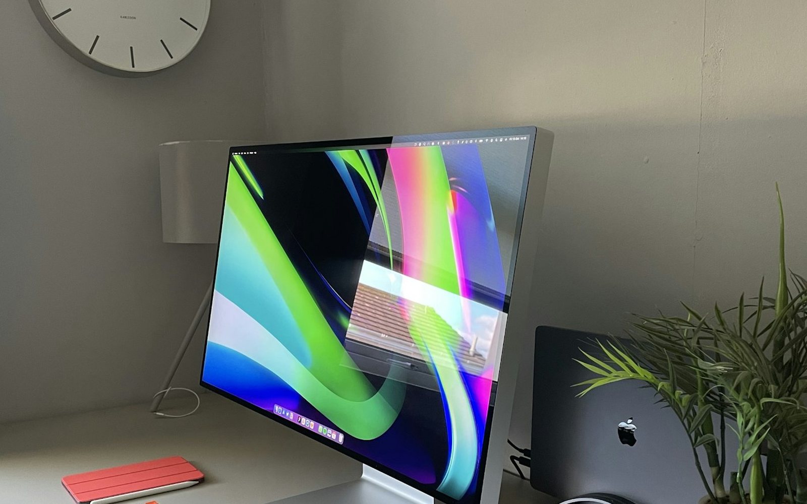 A tidy workspace with a monitor and a wall clock in daylight